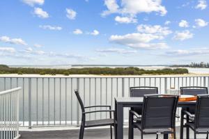 a table and chairs on a balcony with a view of the water at Pumicestone Passage Waterfront Escape in Caloundra +21 photos