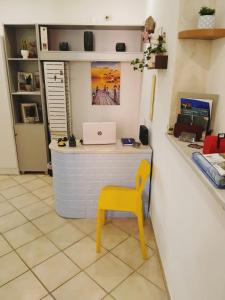 a yellow chair in a room with a desk with a laptop at Casamia-guest house Porto Ercole in Porto Ercole