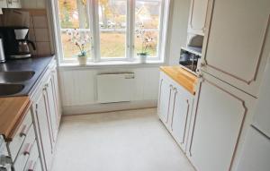 a kitchen with white cabinets and two windows at Holiday Home Sjöhagen Ljungby in Bolmstad