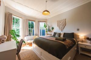 a bedroom with a bed and a desk and windows at The Ocean Villa - Private Sauna in New Plymouth