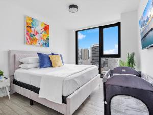 a white bedroom with a large bed and a window at X- Lounge V - High-Rise with Rooftop Pool in Downtown Miami in Miami