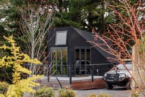 a black tiny house with a car parked in front at Pine Forest Luxury Tiny Cabins in Glenquarry