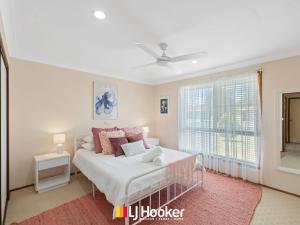 Un dormitorio con una cama blanca y una ventana. en Tully's Beach House, en Iluka