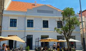 a building with tables and umbrellas in front of it at Ultra Central Piata Libertatii 2 Rooms in Timişoara