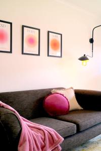 ein Wohnzimmer mit einem Sofa und einem rosa Kissen in der Unterkunft Tranquility in the Meadows - 20 minutes to the City - 6 mins to the beach in Altona Meadows