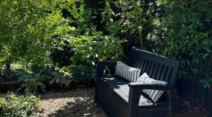 a black bench sitting in front of a garden at Apple Tree Lane Cottage in Bowral