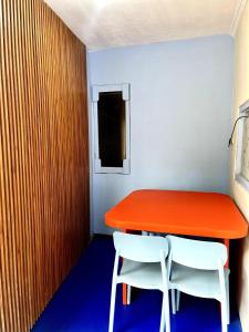 a red table and two white chairs in a room at ZonaBobo Retro Blue Colorful By Belgareti in Cimareme