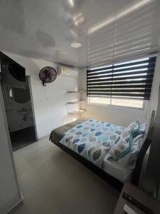 1 dormitorio con 1 cama y ventana con reloj en KlanDestino Hotel, en Santa Marta