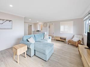 Marg's - Oceanstays - Oceanfront في Brooms Head: غرفة معيشة مع كرسي أزرق وأريكة