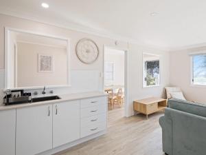 Marg's - Oceanstays - Oceanfront في Brooms Head: مطبخ مع دواليب بيضاء وغرفة معيشة