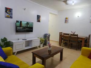 a living room with a couch and a tv on the wall at NimKai Gold Place in Mtwapa