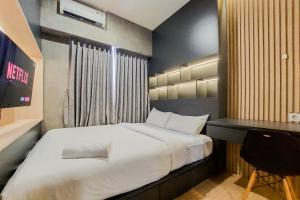 a bedroom with a large bed and a desk at Well Furnished and Cozy 2BR Sky House BSD Apartment By Travelio in Tangerang +13 photos