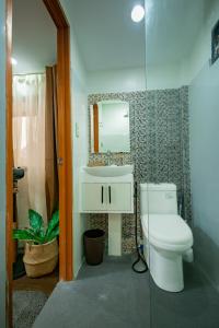 a bathroom with a toilet and a sink and a mirror at Upper Bliss Homestay in El Nido