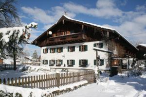 ein weißes Haus mit einem Zaun im Schnee in der Unterkunft Landhotel Huberhof in Schwangau