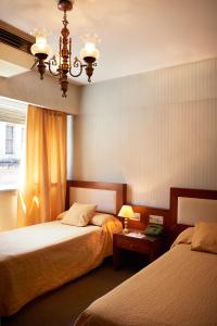1 dormitorio con 2 camas y lámpara de araña en Blanro Hotel en Buenos Aires