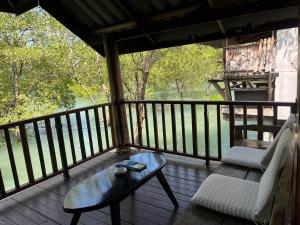eine Veranda mit Sofa und Couchtisch auf einer Terrasse in der Unterkunft Ban Tha Ton Do Koh Yao noi in Ko Yao Noi