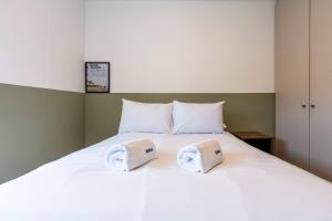 a white bed with two towels on top of it at Dubrovnik 2BR by Geko in Lima
