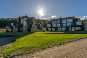 a large house with the sun in the sky at Departamentos Estancia Los Ñires in San Martín de los Andes