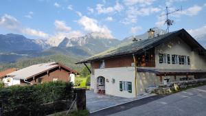 une petite maison avec des montagnes en arrière-plan dans l'établissement Ferienwohnung Kahlersberg, à Schönau am Königssee