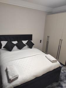 a bedroom with a white bed with black pillows at Sanctum comfy Homes at Kindaruma in Nairobi +28 photos