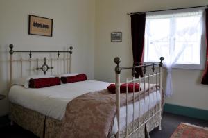 Un dormitorio con una cama con almohadas rojas y una ventana en Shunters Cottage en Waihi