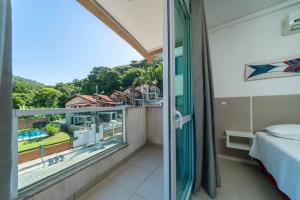 Zimmer mit einem Balkon, einem Bett und einem Fenster in der Unterkunft Apartamento a 150 metros da Praia Bombinhas com 110m2 Natureza e Praia juntos Apt Completo pra toda família com Elevador #Uma verdadeira Experiência# in Bombinhas