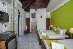 a hotel room with two beds and a television at Ceyloni Lake Residency in Kandy