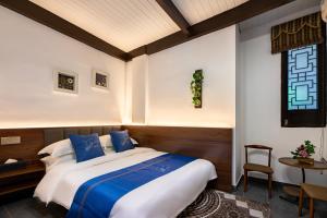a bedroom with a large bed with blue and white sheets at Huangshan Chuyuyuan Manju Homestay in Huangshan