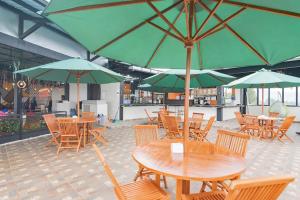 a group of tables and chairs with green umbrellas at Mamifokobo Hotel & Glamping in Sindanglaya