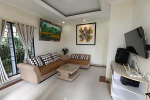 a living room with a couch and a tv at Mamifokobo Hotel & Glamping in Sindanglaya