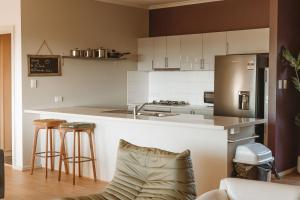 a kitchen with a sink and a counter with stools at The Summit House in Pelican Lagoon