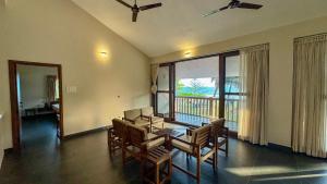 Un comedor con mesa y sillas y un balcón. en Palm Gardens Beach View Villa, en Udupi