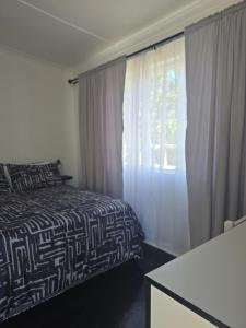 um quarto com uma cama em preto e branco e uma janela em Majhiya on Ferndale apt em Gqeberha