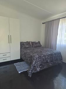 um quarto com uma cama em preto e branco e uma janela em Majhiya on Ferndale apt em Gqeberha