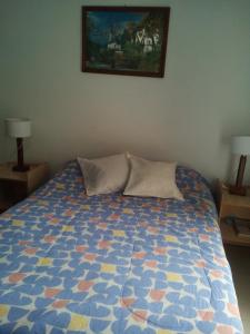 1 cama con 2 almohadas y una foto en la pared en Salta,Departamento Para Visitar la Virgen Del Cerro o Viaje De Placer en Salta