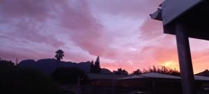 a sunset with a palm tree and mountains in the background at Come Again Self Catering in George