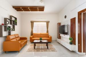 a living room with two chairs and a tv at Mistyblue Suites in Bengaluru
