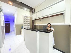 a woman standing at a kitchen counter with a laptop at Griya Inn in Jatingaleh