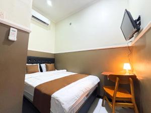 a bedroom with a bed and a tv on the wall at Griya Inn in Jatingaleh