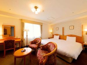 a hotel room with a bed and two chairs at Kanazawa Hakuchoro Hotel Sanraku -Natural Hot Spring- in Kanazawa