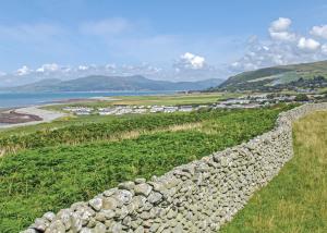 a stone wall on top of a field next to the ocean at Sunbeach Holiday Park in Llwyngwril +18 photos