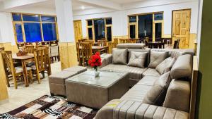a living room with couches and a table with flowers at Hotel Spiti House in Kaza