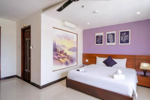 a bedroom with a large bed and a painting on the wall at Quoc Cuong Hotel & Apartment Danang by Haviland in Da Nang