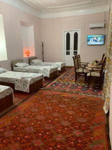 a room with three beds and a table and chairs at Mekhtarin in Bukhara