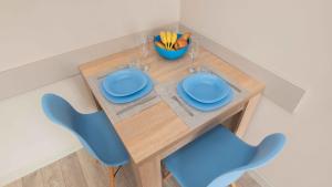 a wooden table with two blue chairs and a bowl of fruit at Студио Булаир 1 с безплатен паркинг in Burgas