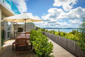 un patio con sombrilla, mesa y sillas en Tahi Lodge - Matakana Coast, en Snells Beach