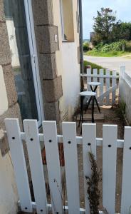 a white picket fence in front of a house at Petite maison tranquille in Pleugriffet