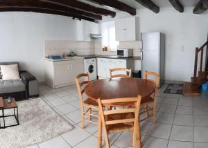 a kitchen and dining room with a wooden table and chairs at Petite maison tranquille in Pleugriffet