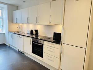 a kitchen with white cabinets and a refrigerator at aday - Pedestrian Beautiful 4 bedroom Apartment in Aalborg