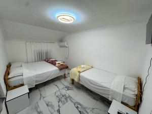 two beds in a room with marble floors at Guest House Besi in Fierzë